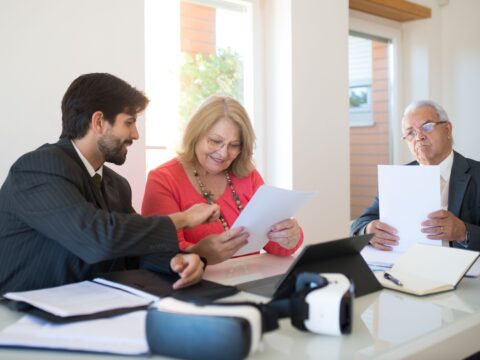 Three professionals collaborate during a business meeting, reviewing documents in a modern office setting.
