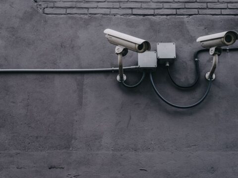 Two surveillance cameras mounted on a concrete wall, highlighting security technology.